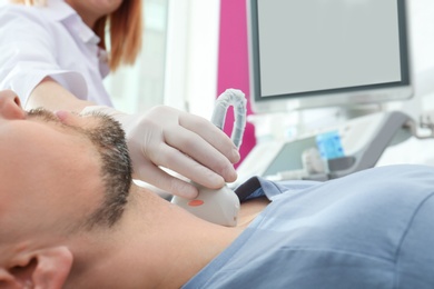 Doctor conducting ultrasound examination of thyroid gland in clinic