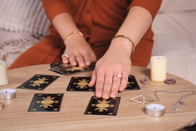 Photo of Soothsayer predicting future with tarot cards at table indoors, closeup