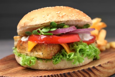 Photo of Delicious burger with tofu and fresh vegetables on wooden board, closeup