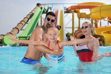 Happy family playing in swimming pool at water park