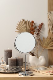 Photo of Mirror, perfume and burning candles on makeup table