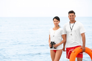Photo of Professional lifeguards with life buoy and binocular at beach