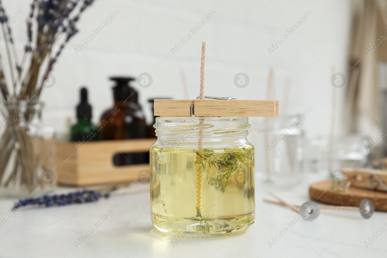 Photo of Glass jar with melted wax on white table. Handmade candle