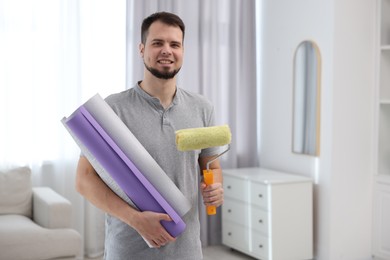 Photo of Man with wallpaper rolls and roller in room