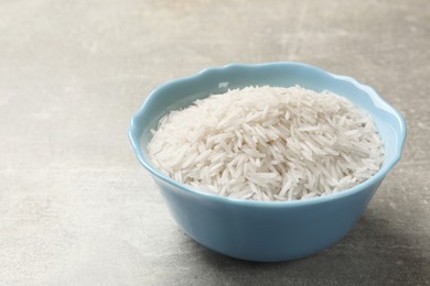 Photo of Raw basmati rice in bowl on grey table, closeup