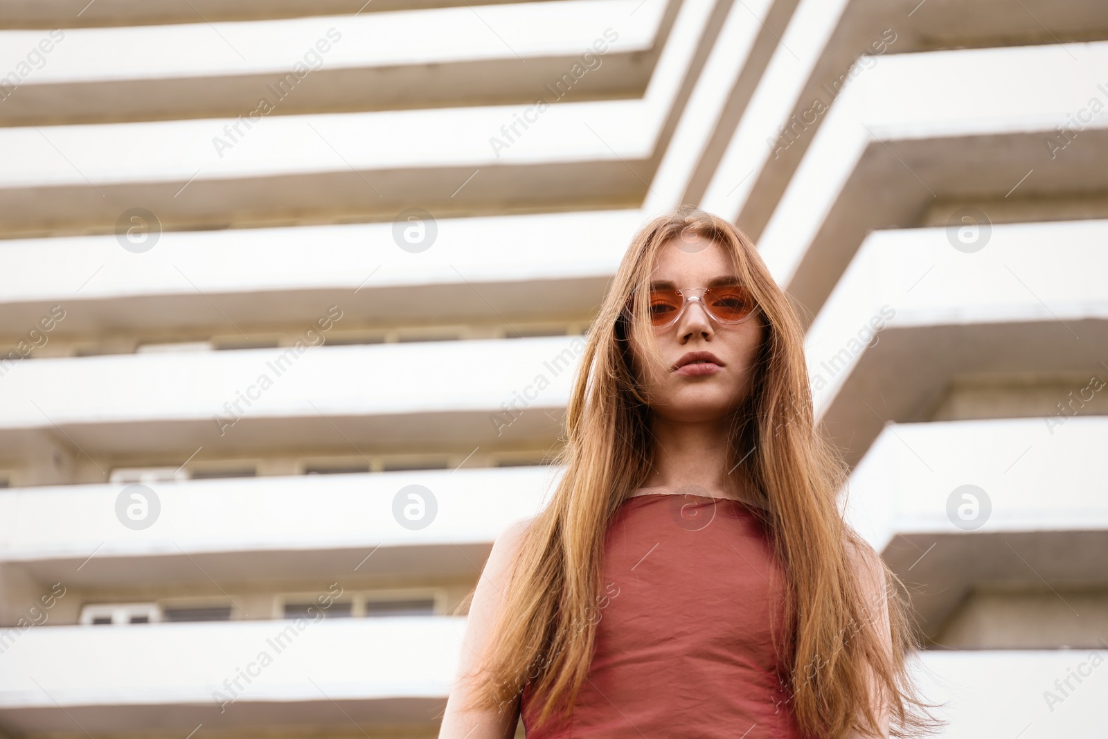 Photo of Beautiful young woman wearing sunglasses at modern building