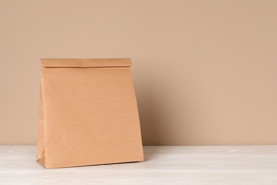 Photo of Paper bag on table against color background. Mockup for design