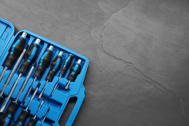 Photo of Set of screwdrivers in open toolbox on dark textured table, top view. Space for text