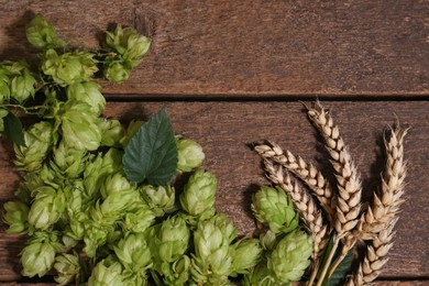 Photo of Fresh green hops and ears of wheat on wooden table, flat lay