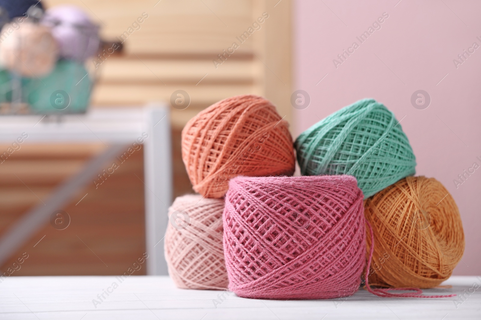 Photo of Colorful clews of threads on table against blurred background, space for text