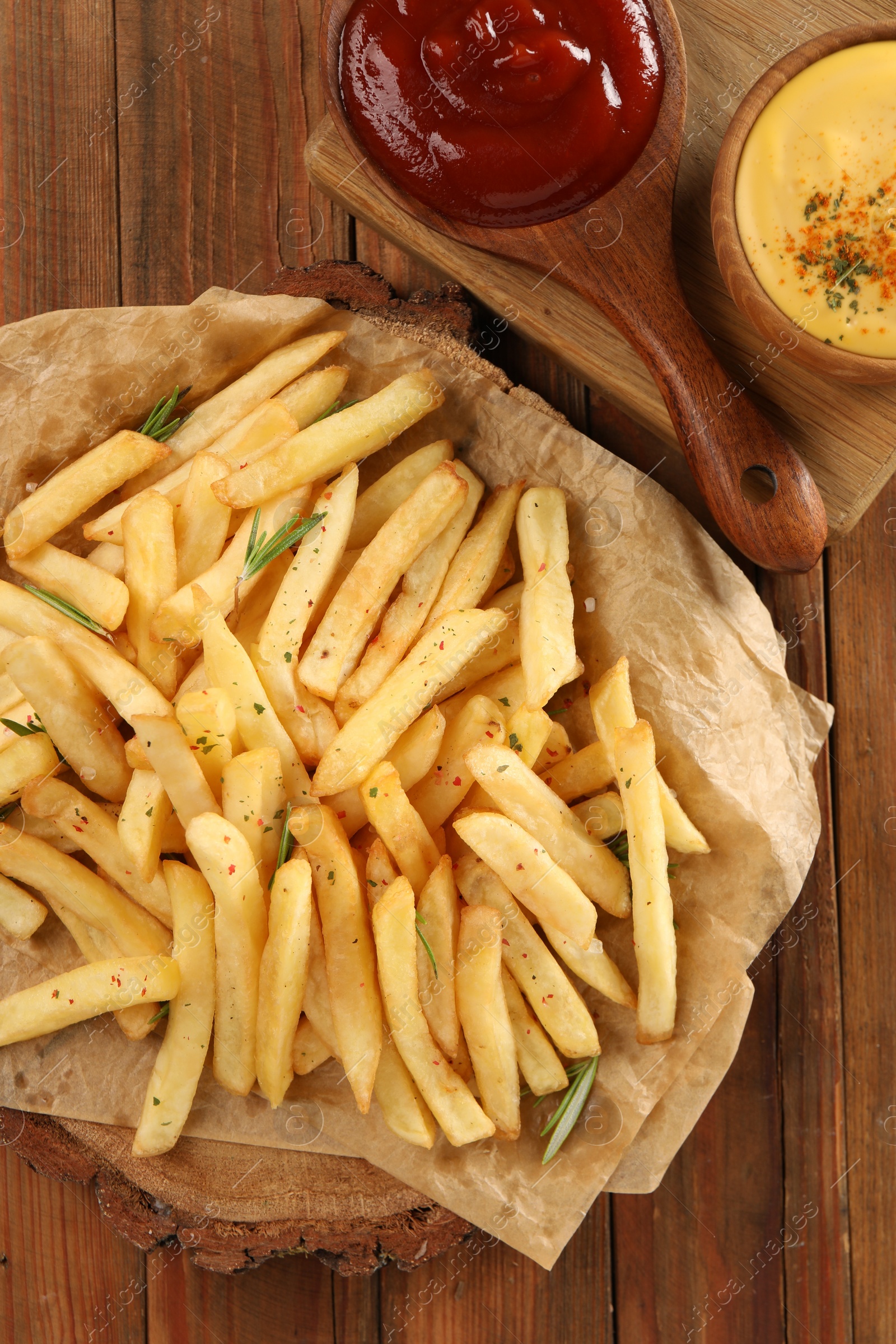 Photo of Delicious french fries served with sauces on wooden table, flat lay