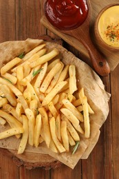 Photo of Delicious french fries served with sauces on wooden table, flat lay