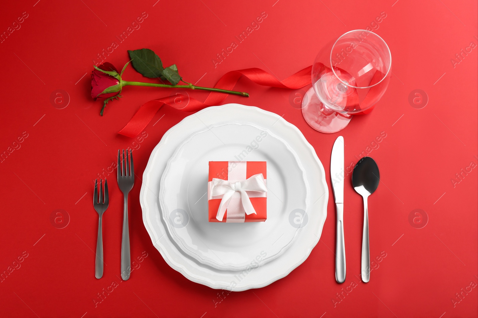 Photo of Beautiful table setting for Valentine's Day dinner on red background, flat lay