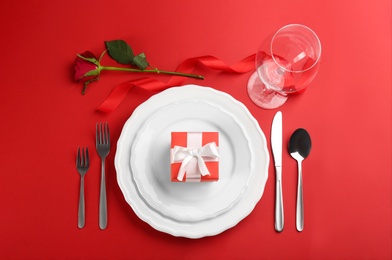 Photo of Beautiful table setting for Valentine's Day dinner on red background, flat lay