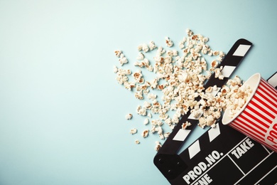 Photo of Tasty popcorn and clapperboard on color background, top view with space for text. Cinema snack