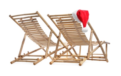 Photo of Wooden deck chairs and Santa Claus hat on white background. Christmas vacation