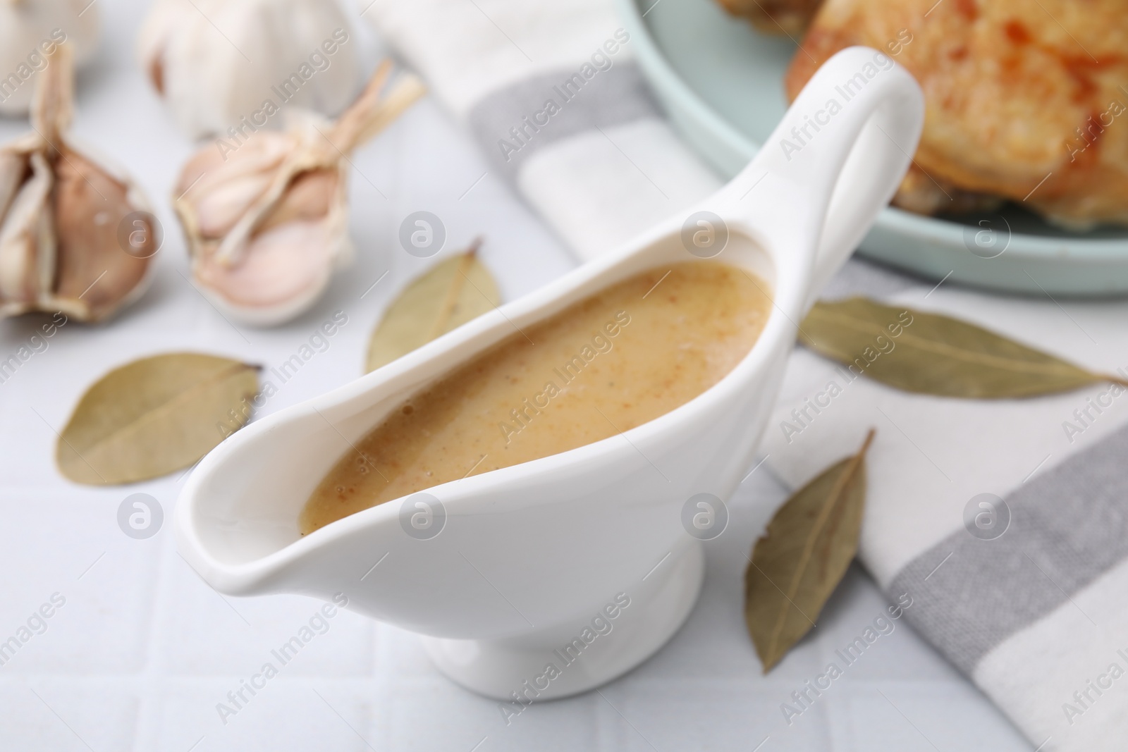 Photo of Delicious turkey gravy in sauce boat on white table, closeup