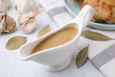 Photo of Delicious turkey gravy in sauce boat on white table, closeup