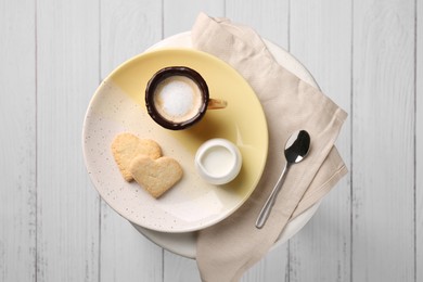 Photo of Delicious edible biscuit cup with coffee, milk and heart shaped cookies on white table, flat lay
