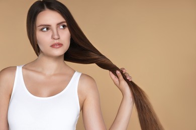 Photo of Young woman with strong healthy hair on beige background