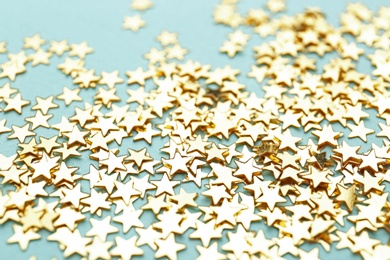 Photo of Confetti stars on light blue background, closeup. Christmas celebration