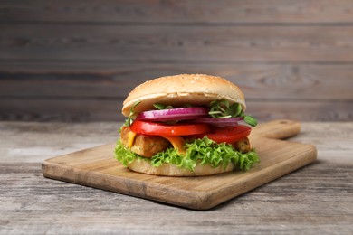 Photo of Delicious burger with tofu and fresh vegetables on wooden table