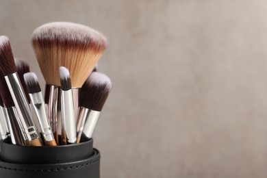 Set of professional makeup brushes on light grey background, closeup. Space for text