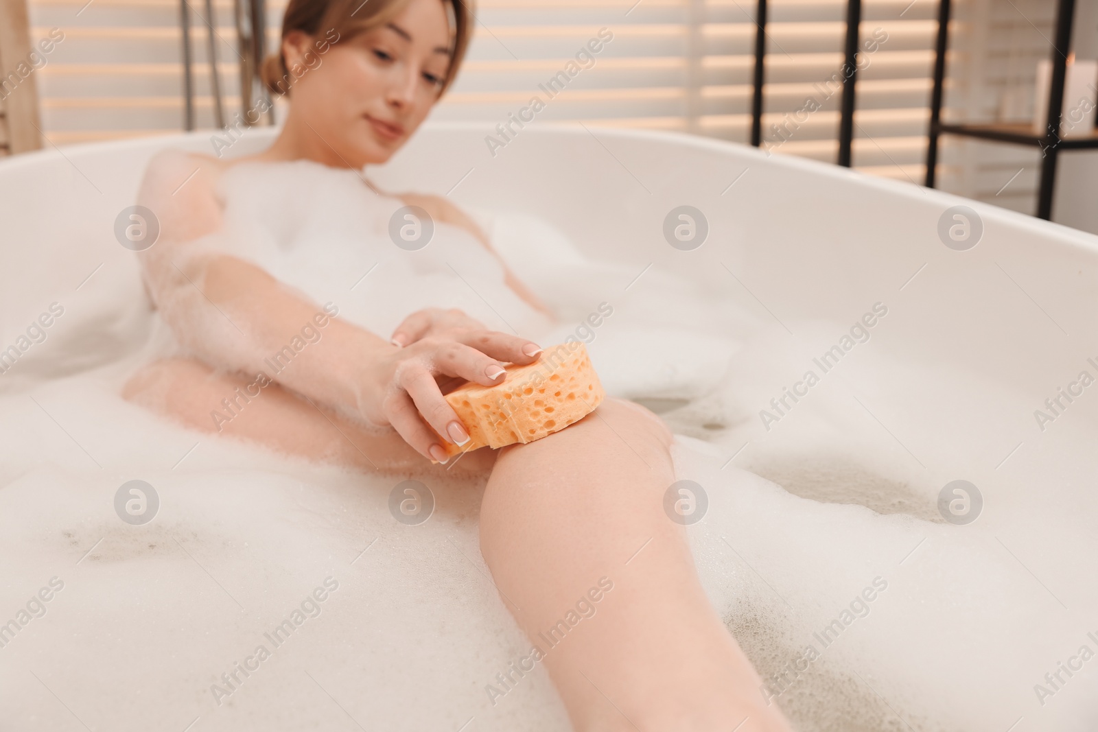 Photo of Woman taking bath with foam in tub indoors, selective focus