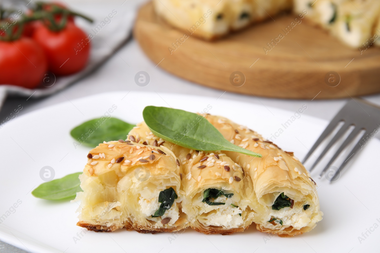 Photo of Piece of delicious puff pastry with spinach on table, closeup