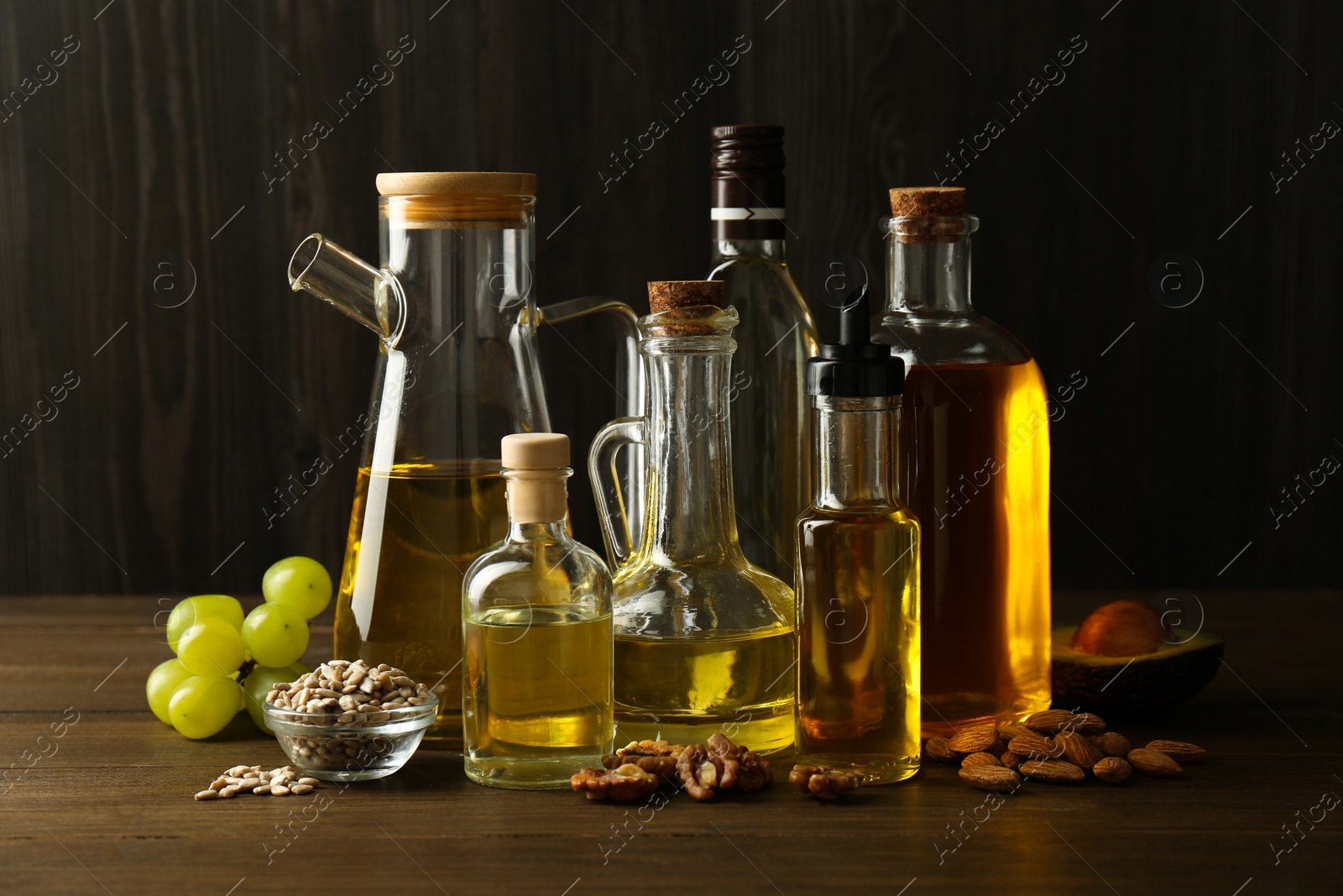 Photo of Vegetable fats. Different oils in glass bottles and ingredients on wooden table