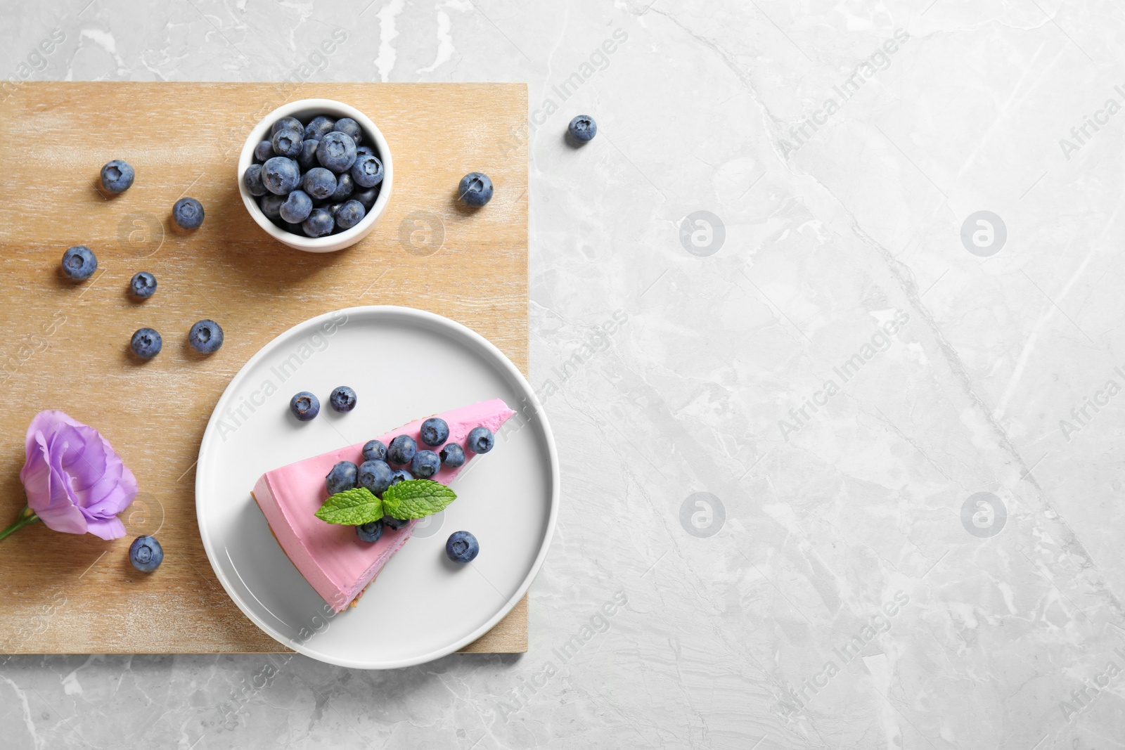 Photo of Flat lay composition of tasty cake and blueberries on light table. Space for text