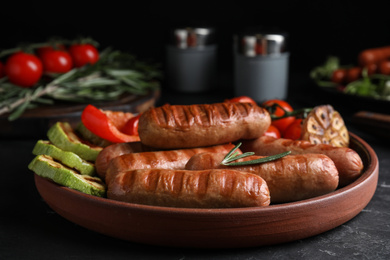 Tasty grilled sausages served on black table