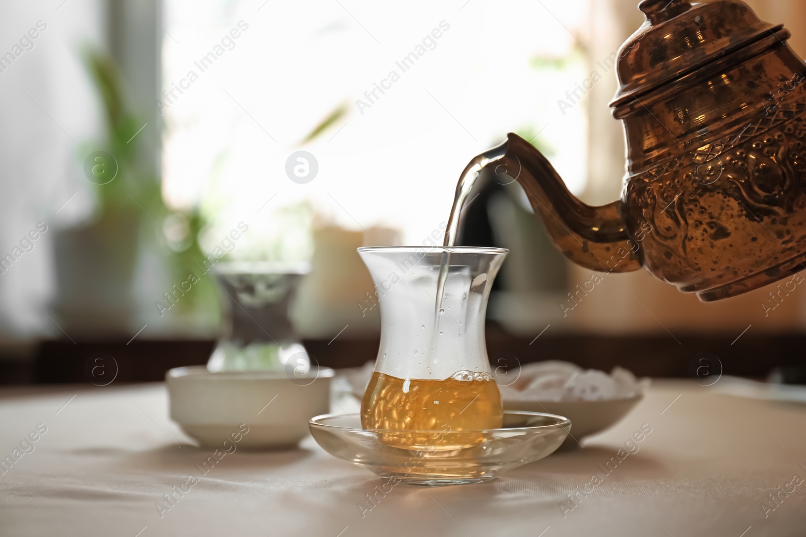 Photo of Pouring hot tea into glass cup on table