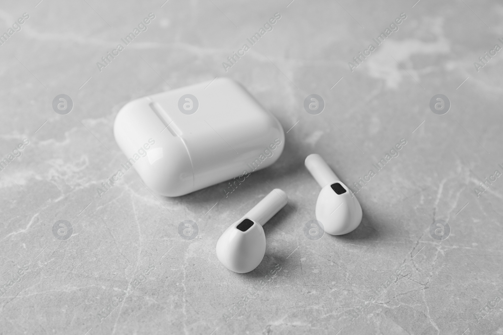 Photo of Wireless earphones and charging case on light grey marble table