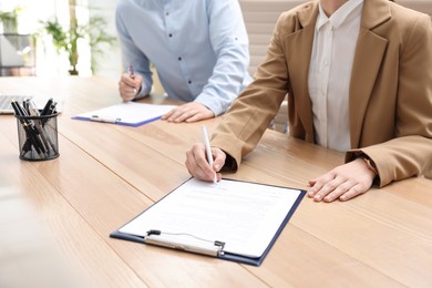 Photo of Woman signing contract at table in office, closeup.