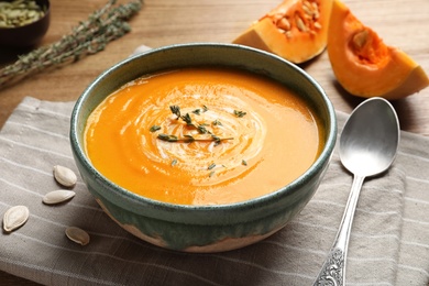 Photo of Delicious pumpkin cream soup in bowl on wooden table