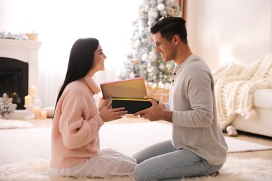 Couple opening gift box in room with Christmas tree