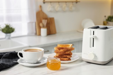 Photo of Breakfast served in kitchen. Toaster, crunchy bread, honey and coffee on white table