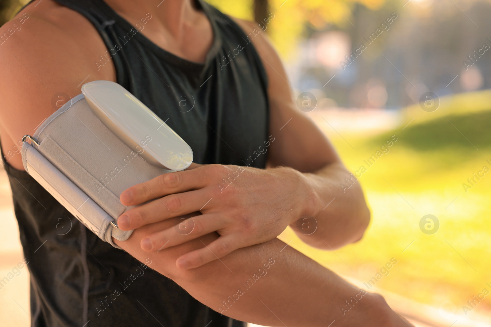 Photo of Man checking blood pressure with modern monitor after training on sunny day, closeup