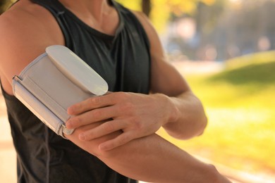 Photo of Man checking blood pressure with modern monitor after training on sunny day, closeup