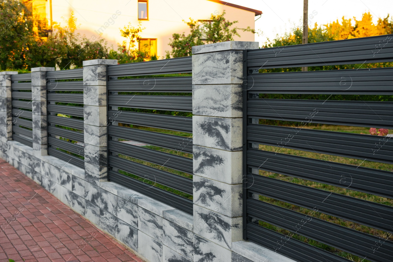 Photo of Beautiful stone fence with iron railing near pathway outdoors