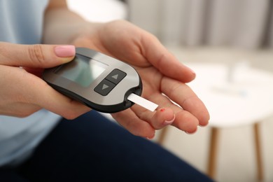 Diabetes. Woman checking blood sugar level with glucometer at home, closeup