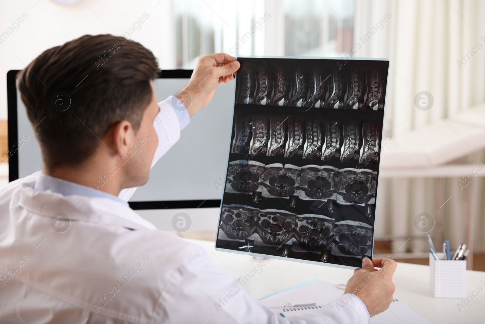 Photo of Orthopedist examining X-ray picture at desk in clinic