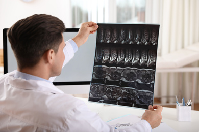 Orthopedist examining X-ray picture at desk in clinic