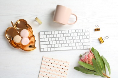 Photo of Creative flat lay composition with tropical flower, macaroons and computer keyboard on wooden background