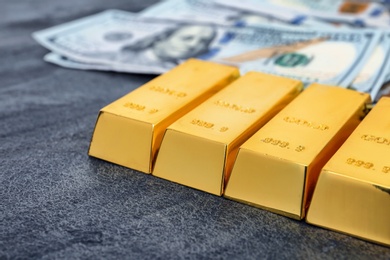 Photo of Gold bars and dollar bills on table, closeup