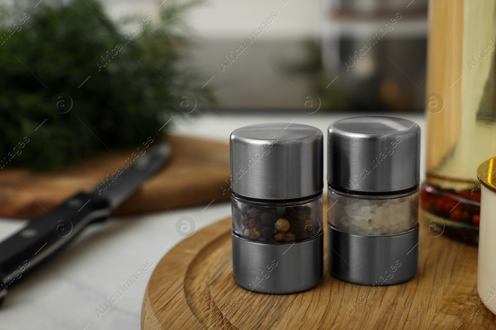 Photo of Salt and pepper mills on wooden board in kitchen. Space for text