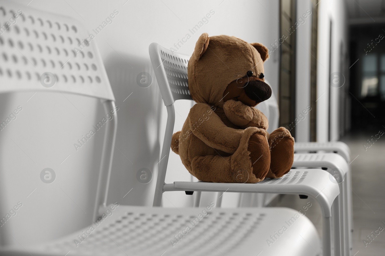 Photo of Cute lonely teddy bear on chair indoors. Space for text