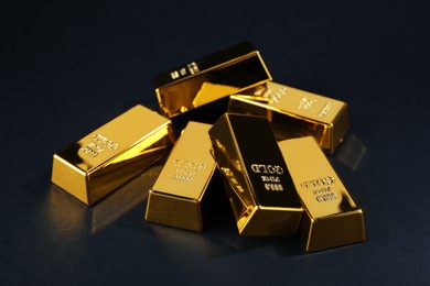 Photo of Many shiny gold bars on black background