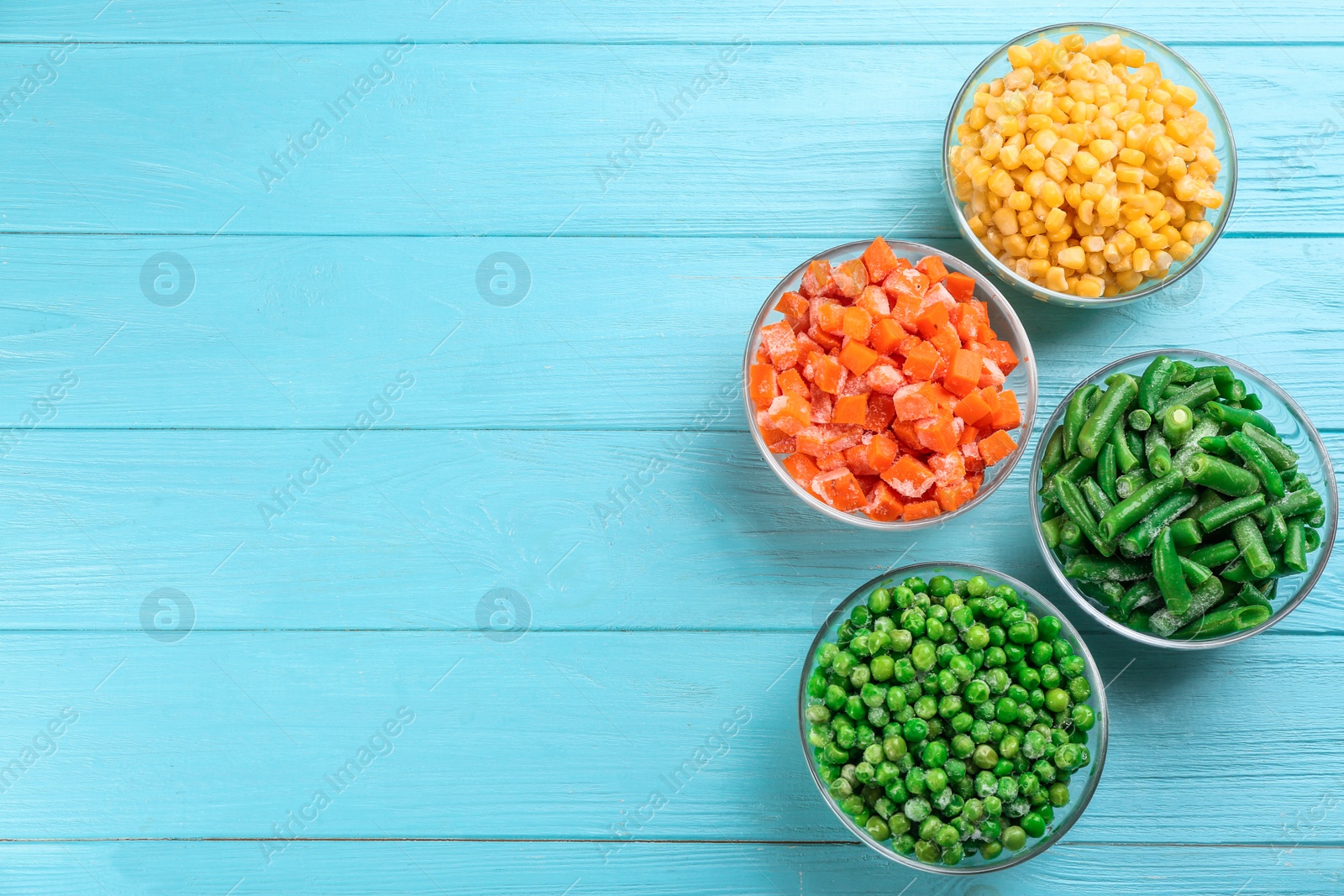 Photo of Different frozen vegetables on light blue wooden table, flat lay. Space for text